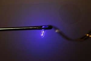 フレキシブルリボンの先端に形成された極小LED。リボンは針の穴に通せる細さ (Credit: John A. Rogers)